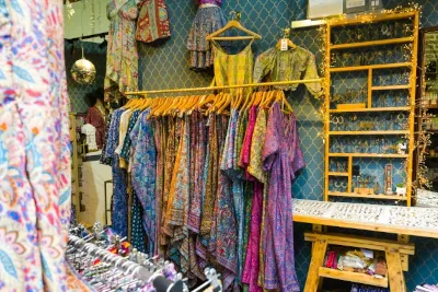 A vibrant and organized rack of colorful secondhand clothing in a thrift store.
