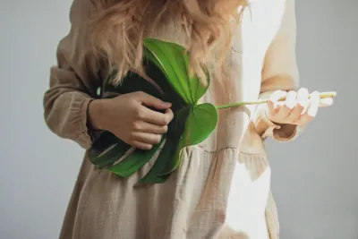 Neatly folded natural-fiber clothing with a green plant resting on top, symbolizing eco-friendly fashion.