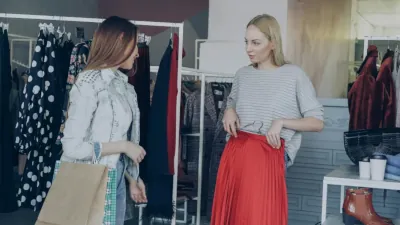 Girls are choosing clothes together while standing near rails in luxurious garments shop
