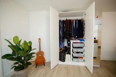 A neatly organized minimalist wardrobe with clothes on hangers and folded on shelves.